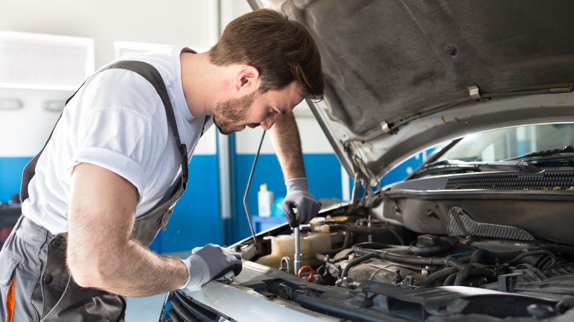 Car mechanic fixing parts of car engine